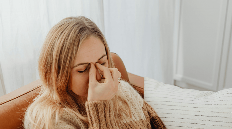 A person pinching the bridge of their nose in pain.