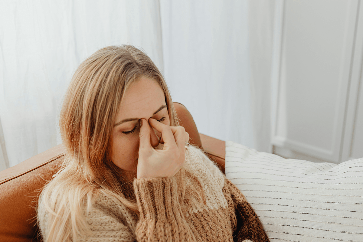 A person pinching the bridge of their nose in pain.