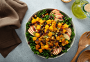 A bright yellow and green fall salad, with apples slices, cranberries and squash.