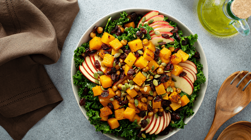 A bright yellow and green fall salad, with apples slices, cranberries and squash.