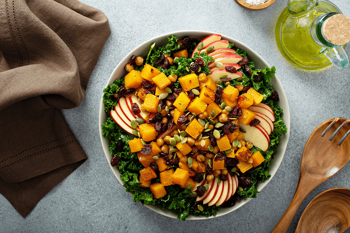 A bright yellow and green fall salad, with apples slices, cranberries and squash.