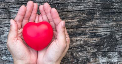 A person holding a heart sculpture in their hand.