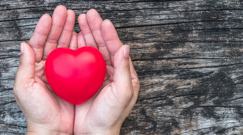 A person holding a heart sculpture in their hand.