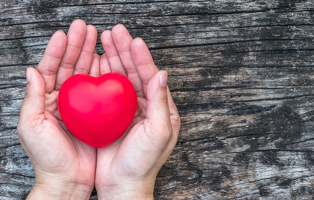 A person holding a heart sculpture in their hand.