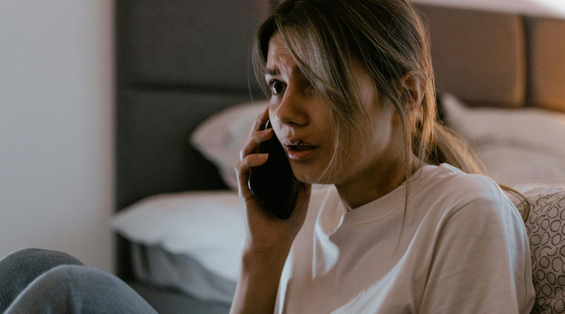 A person talking on the phone with a terrified expression.