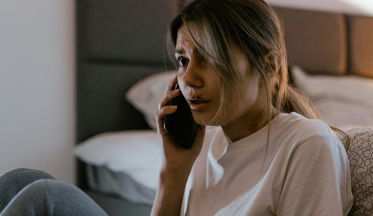 A person talking on the phone with a terrified expression.