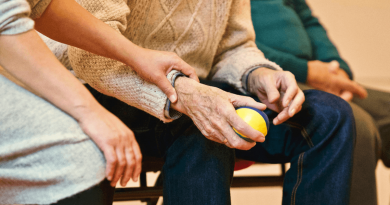 A person holding an older adult's wrist.