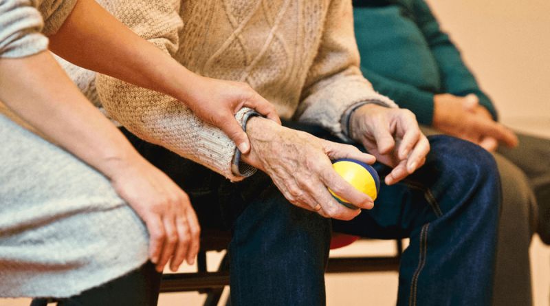 A person holding an older adult's wrist.