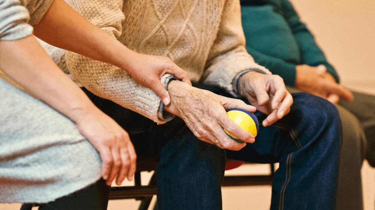 A person holding an older adult's wrist.