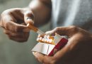 A pair of hands pulling a cigarette out of a pack.