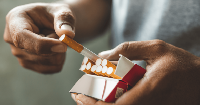 A pair of hands pulling a cigarette out of a pack.