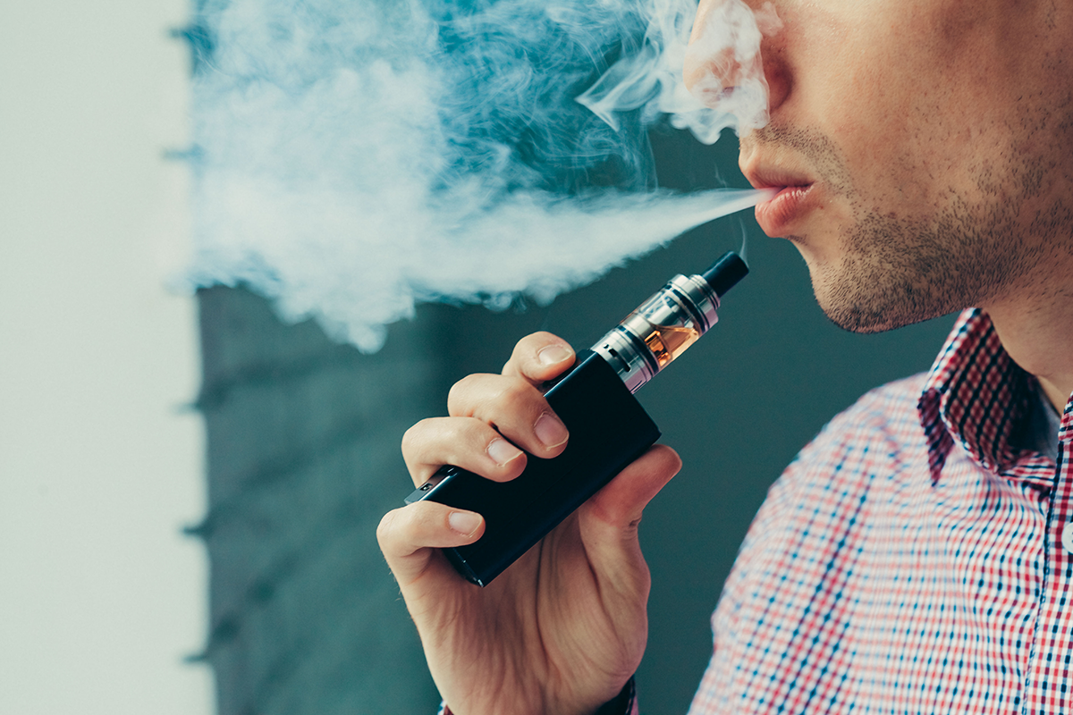 A person exhaling a large smoke cloud from their vape pen.