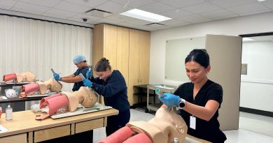 Three students practicing breathing assistance with mannequins.