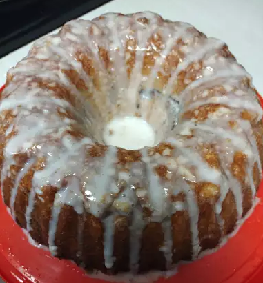 A brown Bundt cake with white icing dripped along the top.