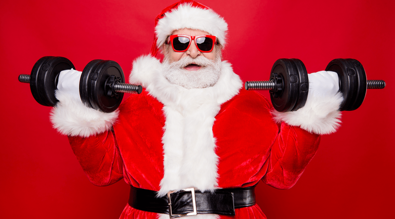 Santa Claus wearing red-rimmed glasses and lifting weights. He has an excited expression as he curls dumbells.