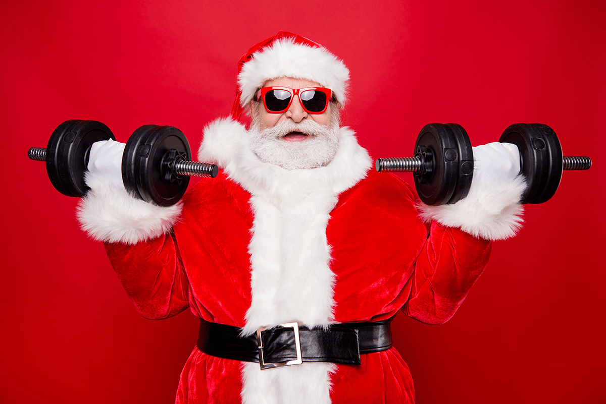 Santa Claus wearing red-rimmed glasses and lifting weights. He has an excited expression as he curls dumbells.