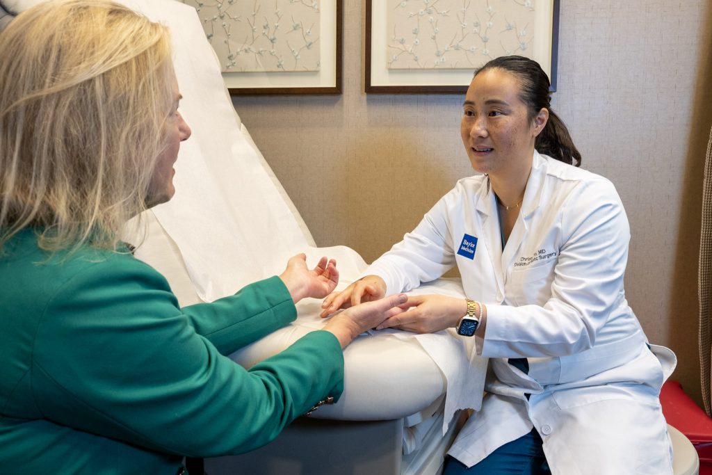 Dr. Christine Yin examines Holly Shilstone's hands in an exam room.
