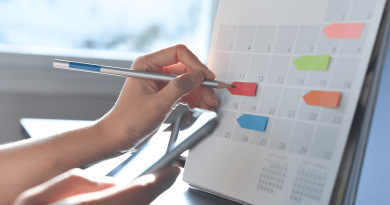 A person marking a desk calendar with sticky note arrows as labels.