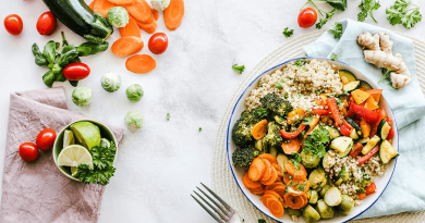 A vibrant and colorful salad made of carrot slices, cherry tomatoes, broccoli, squash, brussels sprouts and couscous.