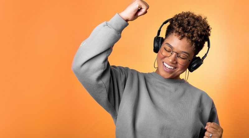A person wearing headphones pumping a fist happily.