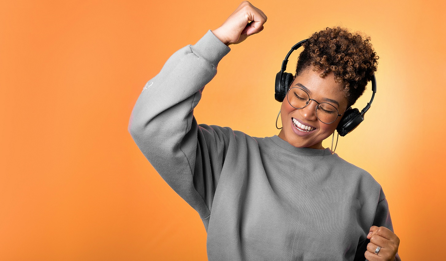 A person wearing headphones pumping a fist happily.