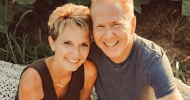 Keri Carlson sitting outdoors in the sun next to her husband.