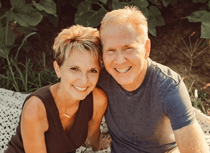 Keri Carlson sitting outdoors in the sun next to her husband.