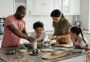 A family in the kitchen putting together a meal, with bowls of cereal, avocados and slices of toast.