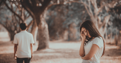 A person walking away from another person, who is holding their head and looking sad.