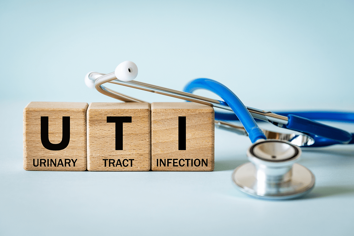 A stethoscope next to three wooden blocks. The blocks have one word each, reading Urinary Tract Infection.