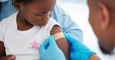 A Band-Aid being applied to a child's arm after they were given a vaccine.