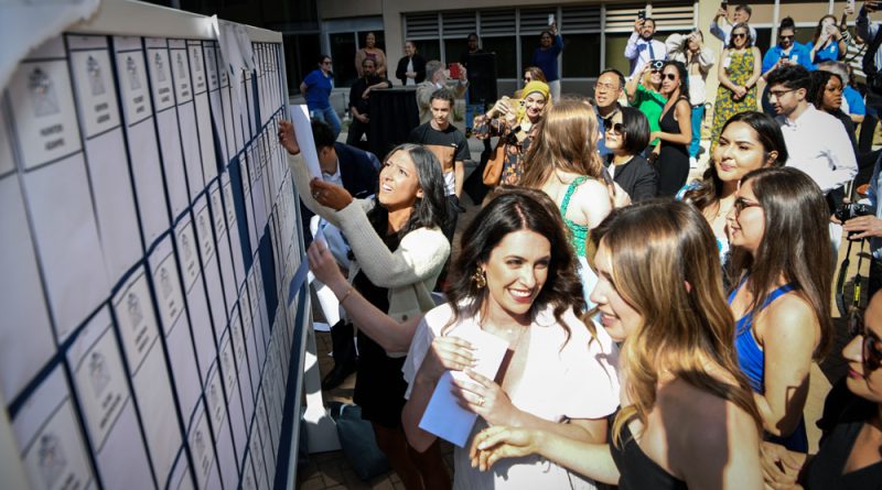 Fourth-year medical students grabbing their matches off the Match board.