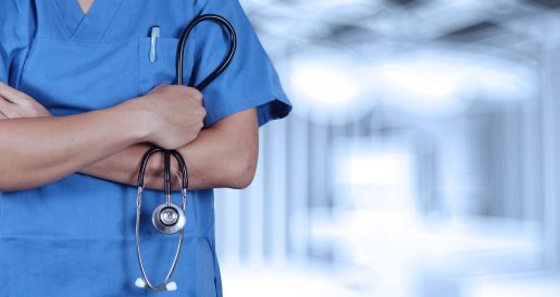 Doctor in scrubs holding stethoscope.