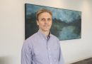 Patient Zach Wawrzgnack standing in front of a painting in the McNair Building at Baylor Medicine.