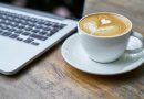 Cup of coffee next to a laptop.