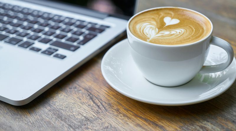Cup of coffee next to a laptop.