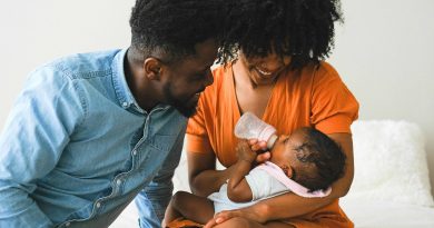 Parents feeding and looking at their baby.