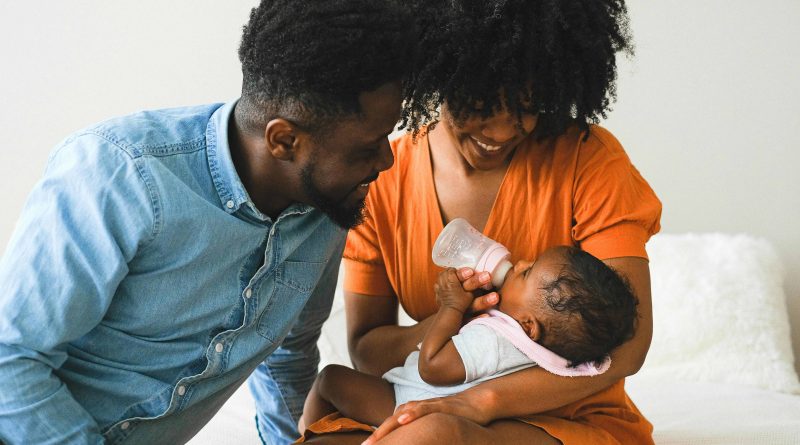 Parents feeding and looking at their baby.
