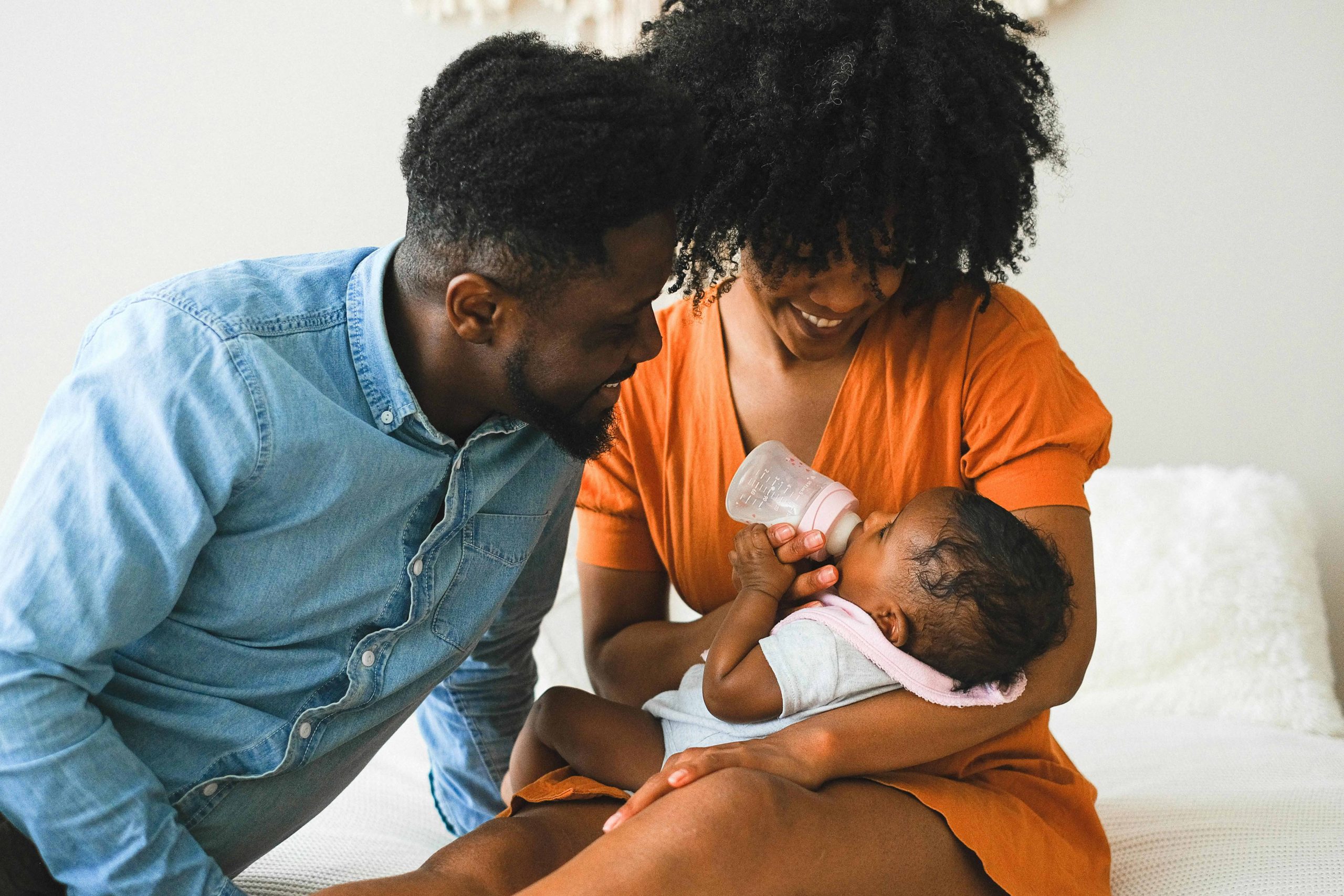 Parents feeding and looking at their baby.