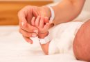 Mom and newborn hands touching.
