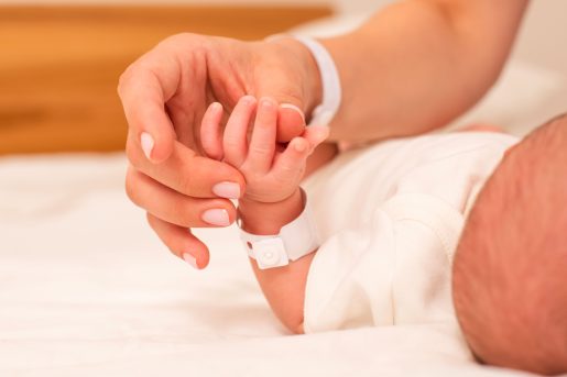Mom and newborn hands touching.
