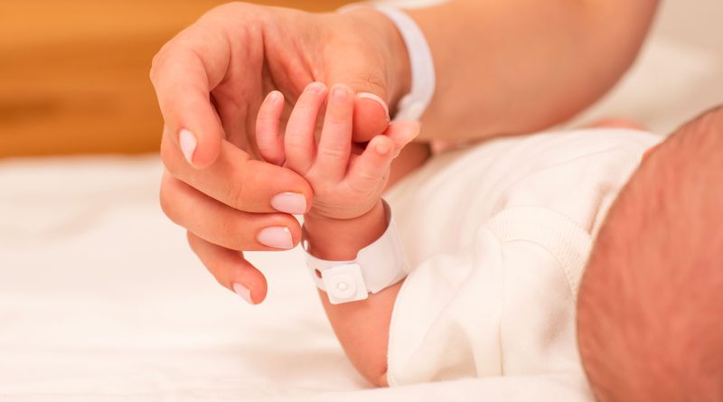 Mom and newborn hands touching.