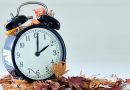 Image of autumn Time Change, Fall back concept, Dry leaves and vintage alarm Black Clock on wooden table outdoors at afternoon