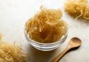 Close up of golden dried Sea Moss in a clear bowl with a wooden spoon.