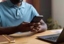Man at desk scrolling on phone.