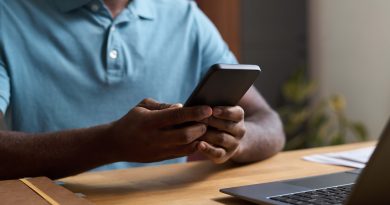 Man at desk scrolling on phone.