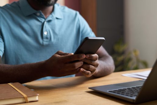 Man at desk scrolling on phone.