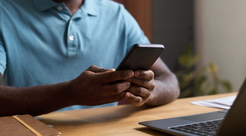 Man at desk scrolling on phone.