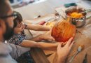 Little girl and her father holding a Halloween pumpkin. Family spending time together.