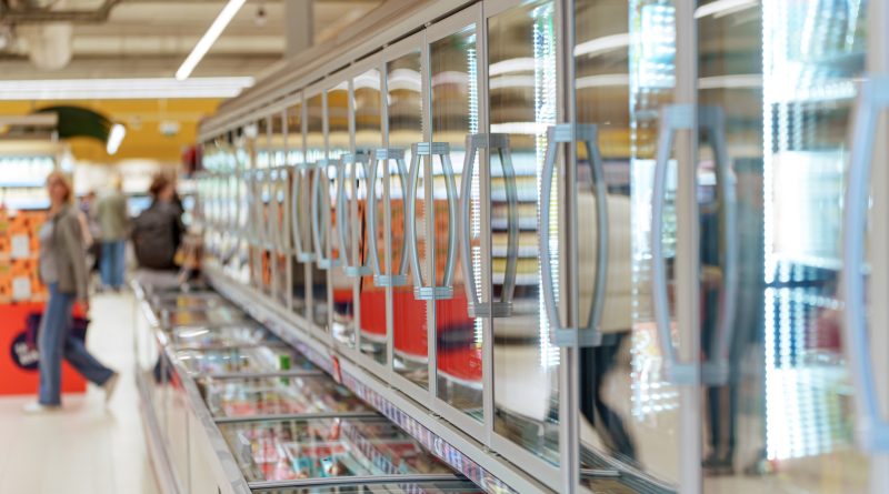 Frozen food aisle with glass door freezers in supermarket